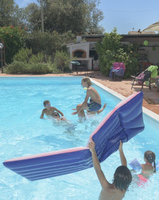 kids playing in the pool dive and use an inflatable mattress
