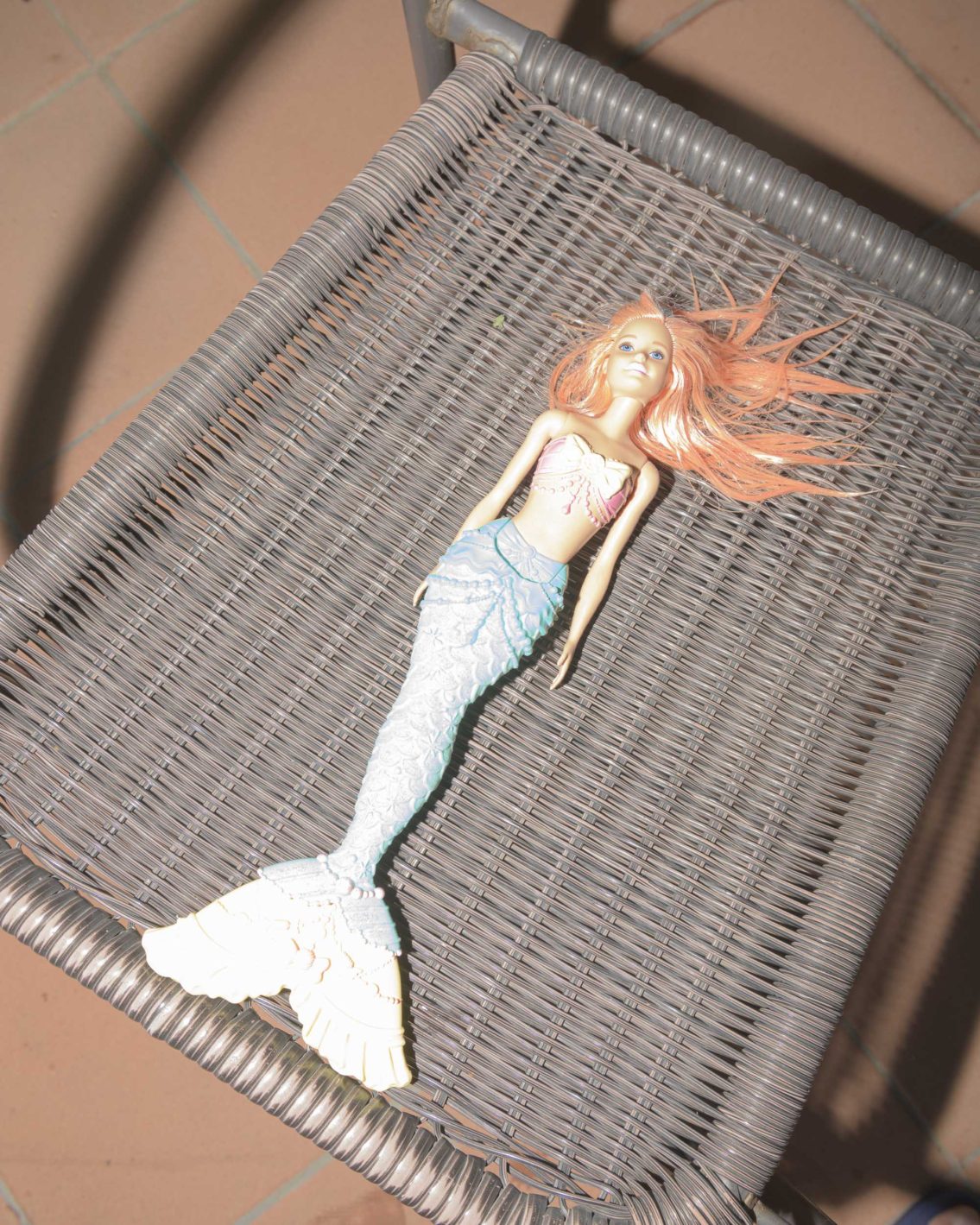 photograph of barbie's little mermaid toy on a plastic chair