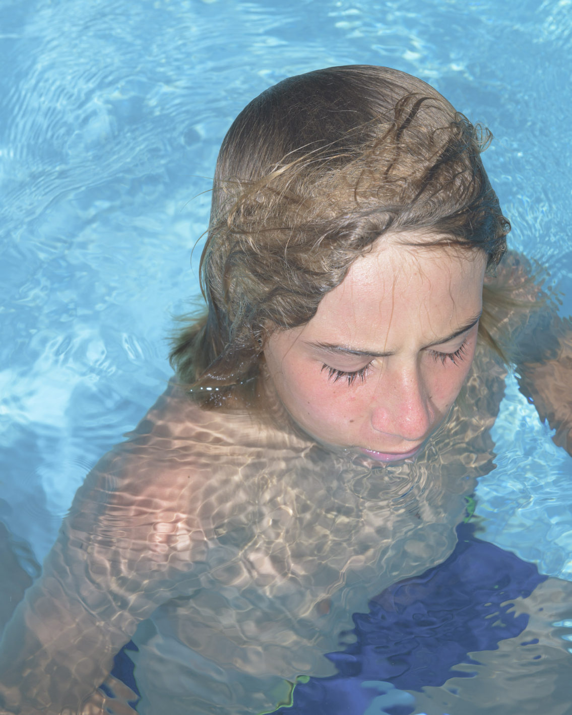 photograph of a blond boy with very long eyelashes in the pool